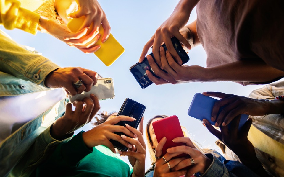 gruppo di ragazzi in cerchio, ogni ragazzo ha uno smartphone in mano